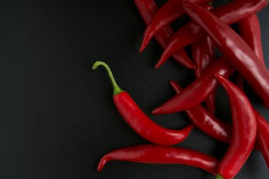 Arka planda siyah taş bir tabakta kırmızı biber, tariflerin ve yemeklerin hazırlanması için çiğ yemek.