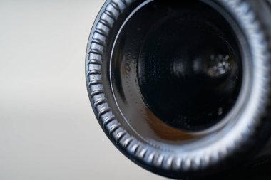 Bir şişe şarap açan bir tirbuşonun yakın çekimi. Mantar aletin siyah metal spirali tarafından delinir, beyaz arka plandaki siyah şişeden çıkarmaya çalışır..