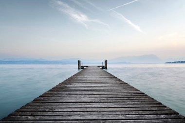 Gölün berrak mavi sularına uzanan eski bir ahşap iskele. Dalgaların tatlı sesiyle doğanın sakin ve huzurlu sessizliğine giden ıssız bir yol..