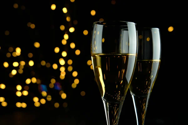 Two glasses of sparkling wine or champagne to celebrate Party or Anniversary with a yellow bokeh effect on dark background.
