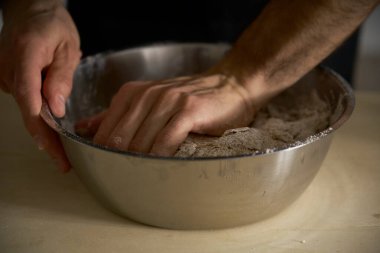 Güçlü adamın elleri ekmek, makarna, pasta ya da pizza yapmak için hamur yoğurur. Mutfağında ev yapımı makarna geleneğini sürdürüyor. Beyaz un bulutu toz gibi uçuyor..