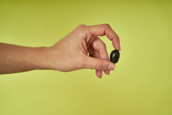 the hand shows black olives on a green background                     