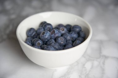 Beyaz ve siyah mermer bir masada bir grup taze yabanmersini.. 