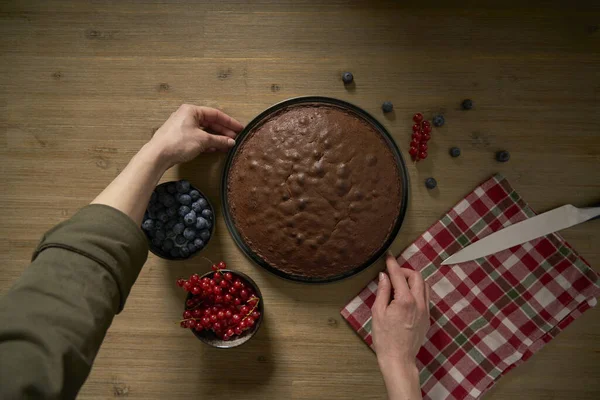 自慢のコックの女性は彼女がちょうど彼女の台所で焼いた自家製チョコレートケーキを示す 彼女はブラックベリー 赤スグリ 粉砂糖とダークチョコレートで甘いパン屋を飾るでしょう ストックフォト