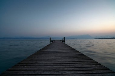 Gölün berrak mavi sularına uzanan eski bir ahşap iskele. Dalgaların tatlı sesiyle doğanın sakin ve huzurlu sessizliğine giden ıssız bir yol..