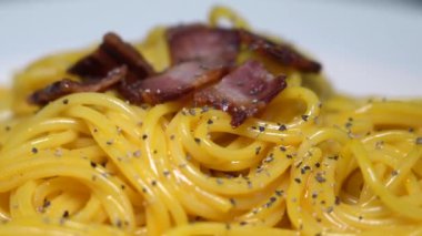 İtalyan kültürünün geleneksel bir makarna yemeği olan spagetti carbonara taze yumurta sarısı, orijinal rendelenmiş pecorino romano, çıtır pastırma ve karabiber..