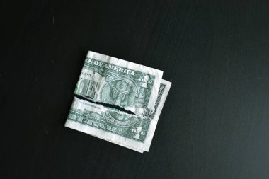 Yırtılmış bir banknot siyah arka planda bir dolar değersizleştirilmiş. Kötü paraya yakın çekim. Doların çöküşü. Devalüasyon. Düşen para birimi.