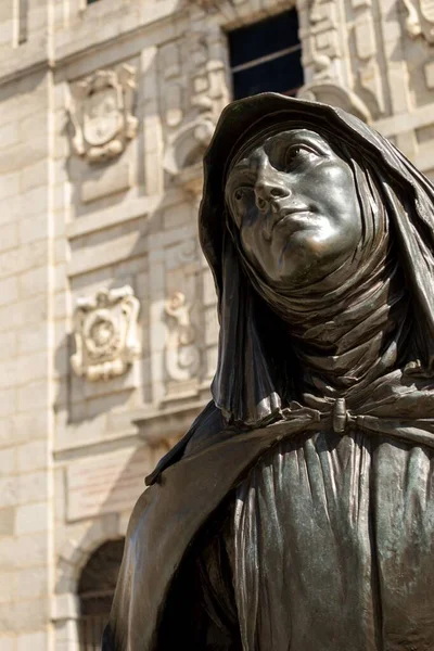 AVILA, SPAIN - 14 Ağustos 2020: Güneşli bir günde adını taşıyan kilisenin önündeki Aziz Teresa 'nın bronz heykelinin seçici odak noktası