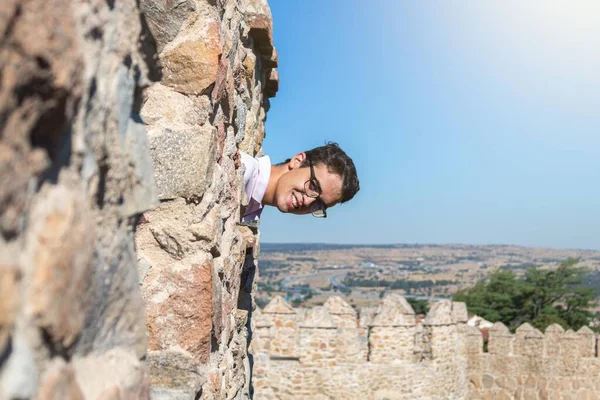 日当たりの良い風景の中で城壁の一部から頭を突き出している少年 — ストック写真