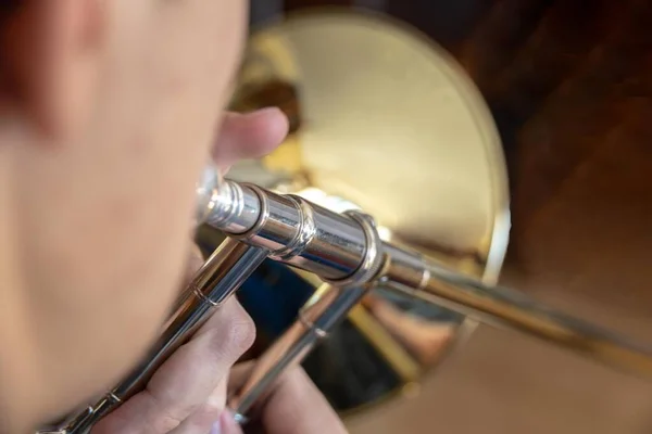 Altın pirinç trombon çalan bir gencin seçici odağı