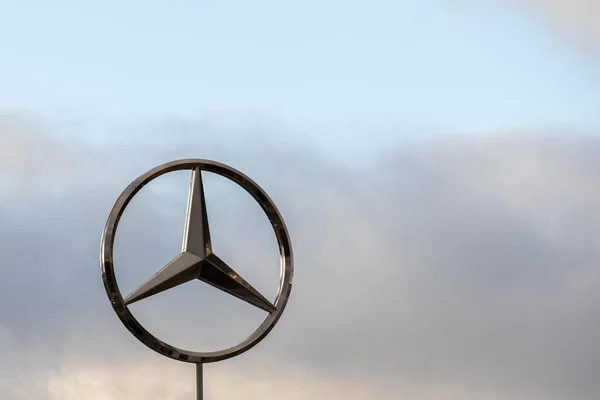 Burgos, ESPAÑA - 06 de diciembre de 2020: Logotipo de la marca de coches Mercedes Benz con un cielo nublado en el fondo — Foto de Stock