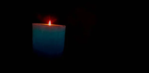 Enfoque selectivo de una vela azul encendida con destellos en el signo oscuro de reflexión y sentido religioso —  Fotos de Stock