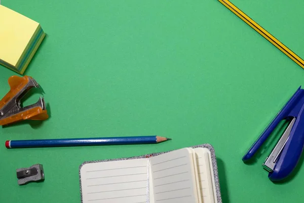 Green background model with stationery objects such as staplers, pens, notebooks — Stock Photo, Image