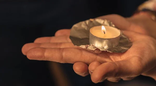 Enfoque selectivo de una vela encendida apoyada en la mano con un sentido religioso — Foto de Stock