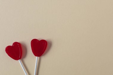 Şubat 'ta, krem rengi arka plan sevgililer günü konseptinde iki kırmızı kalp şekilli lolipopun seçici odağı