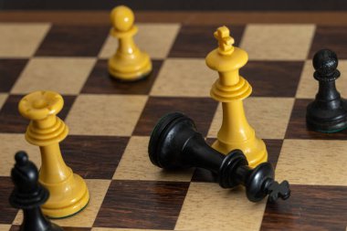 Satranç tahtası oyununda beyaz kralın ayaklarının dibinde sona eren kralı simgeleyen siyah tahta bir taşın seçici odağı.