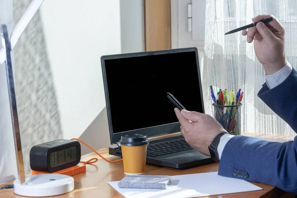 Mavi takım elbiseli bir adamın cep telefonunu izlediği ve laptopunun önünde sosyal ağlara bağlandığı seçici odak noktası.