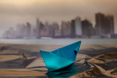 Bulutlu bir günde bulanık bir geçmişi ve sisli New York şehrinin mavi kağıt teknesinin seçici odak noktası