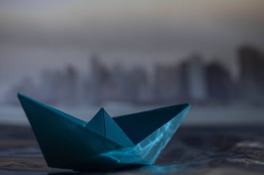 Yağmurlu ve sisli bir günde mavi kağıttan bir teknenin ve New York Sky hattının seçici odağı