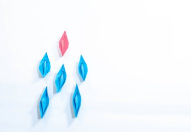 Pembe kağıt teknesi olan bir kadının liderlik konsepti beyaz arka planda blues 'un arasında lider olması..