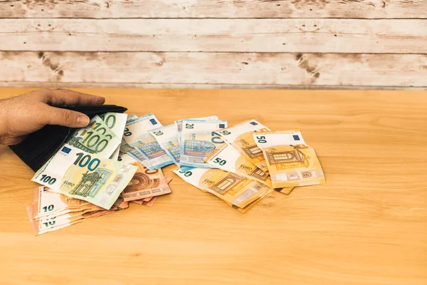 Bir kişinin seçici odak noktası cüzdanı ve Avro banknotları ile çeşitli miktarlarda para tahtadan bir masa üzerine yerleştirilir ekonomi kavramı.