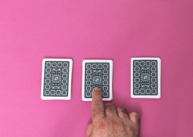 Fuşya pembe arka plan kumar ve bahis salonu konseptine bahis yatırmak için kart işaretini işaret eden seçici bir el.