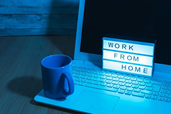 Laptop computer and coffee cup along with a light box indicating Work from home social distant work in time covid19 concept health with bluish light