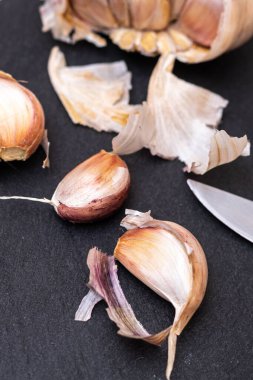 Siyah tahta üzerinde karanfil sarımsağı kesmeye hazır bir bıçakla