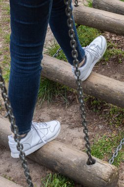 Ağaç gövdelerinden yapılmış bir köprüden geçen bacakların detaylarına odaklanın. Proje zorlukları, hırs ve meydan okumaya başlayın.