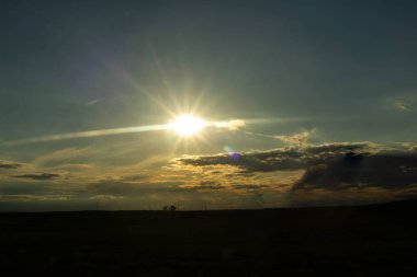 Yoldan panoramik bir manzara. Güneşin karşı ışığı bulutlara karşı bulutsuz bir günde bir yıldız oluşturuyor..