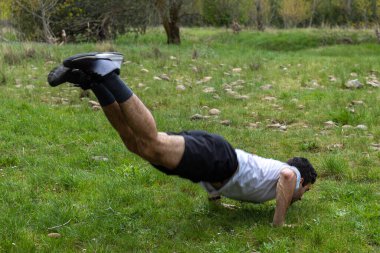 Açık hava sporları konsepti olarak doğanın ortasında atlayan bir gencin seçici odak noktası..