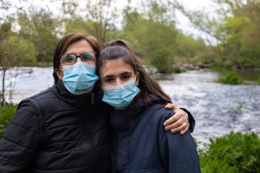 Koronavirüs için maskeli bir anne ve kızın seçici odak noktası su kavramı olan doğa sağlığı ile kendi portrelerini çekmeleri.
