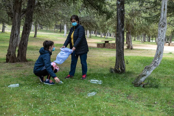 Kadın ve kız geri dönüşüm konseptine atılan plastik şişeleri toplayarak ormanı temizlemeye gönüllü oluyorlar.