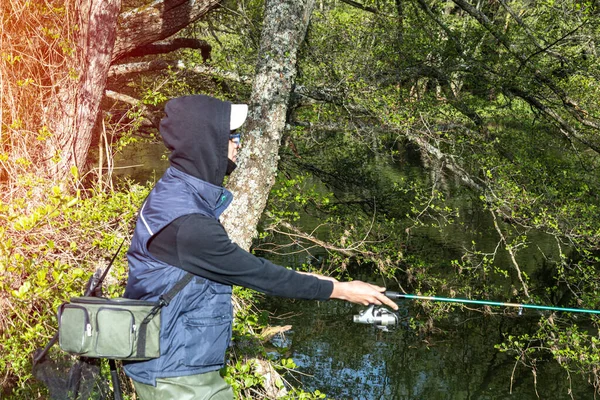 在溪边或河岸上戴着帽帽的少年的选择性焦点 用篮子把钓竿和钓丝一起抛入河里 用复制的空间捕捞鳟鱼 — 图库照片