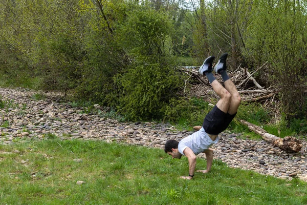 Joven Atleta Pantalones Cortos Realizando Saltos Acrobáticos Flexiones Hierba Entorno —  Fotos de Stock