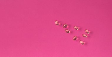 Fotokopi alanı olan saydam ilaç kapsülleri pembe arka plan sağlık konseptine saçılmış durumda.