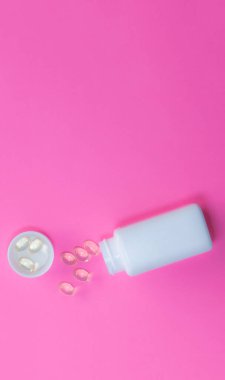 Beyaz, saydam omega-3 vitamin tabletleri gibi bir şişe gözyaşı, fotokopi alanı ile birlikte pembe çarşaf sağlık konsepti diyetinin üzerine döküldü.