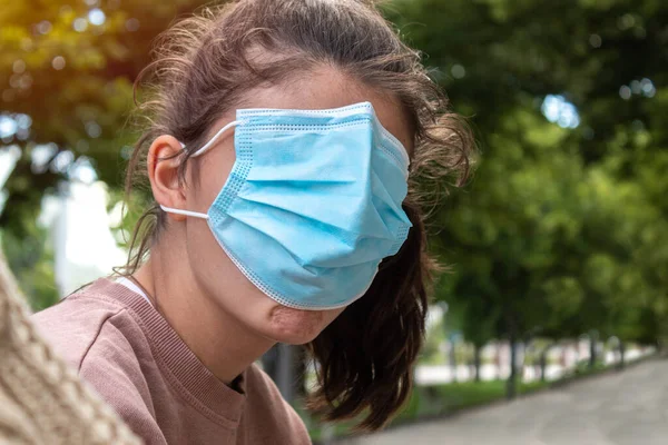 portrait of a teenage girl covering her entire face with a blue mask so as not to be identified with selective focus.