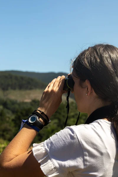 在阳光灿烂的日子里 一个年轻的白种人姑娘带着一副双筒望远镜在夏令营里观看风景 — 图库照片
