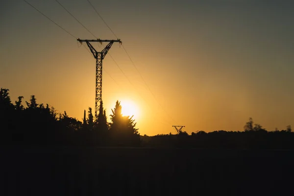 Silhouette of a high voltage electric tower in a sunset with selective focus electric energy concept