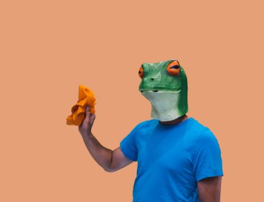 Turuncu mendilli kurbağa maskeli bir jest veya temizlik için bez veya turuncu arka planda fotokopi alanı olan toz konsepti temizleyici.