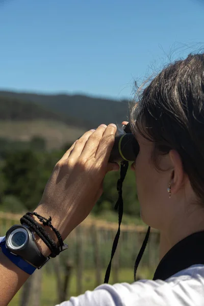 在一个阳光灿烂的日子里 一个女孩用双手拿着一副双筒望远镜 细细地观察着山水的景色 — 图库照片