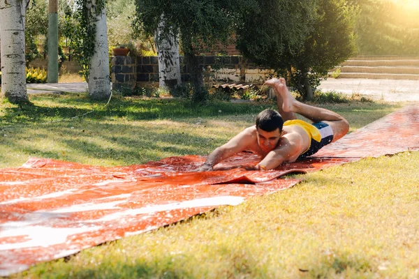 Tiener Jongen Een Badpak Springen Van Een Zeep Water Glijbaan — Stockfoto