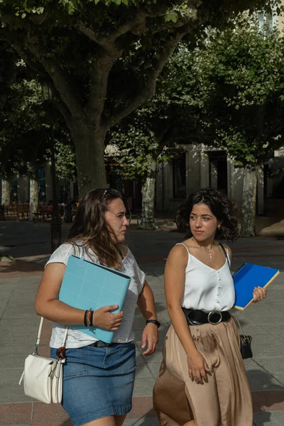 キャンパスや大学に行く途中の晴れた日に街を歩いている2人の若い学生の女の子 — ストック写真