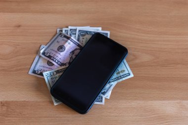akıllı cep telefonu bir doların üstüne yerleştirilmiş para bir masanın üzerinde