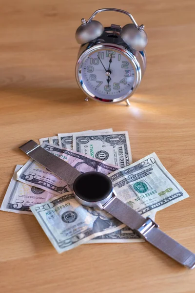 Dinero en dólares colocado en una mesa con un reloj analógico y un reloj digital — Foto de Stock