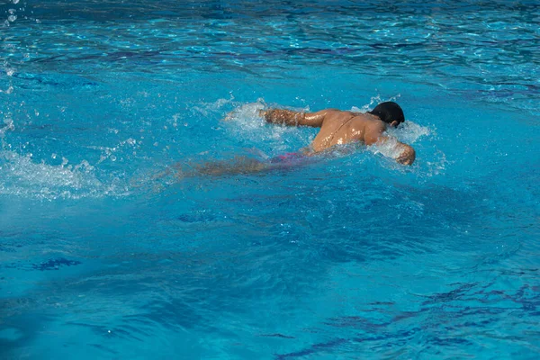 Young man swimming breaststroke with swimsuit in a pool with copying space — Stock Photo, Image