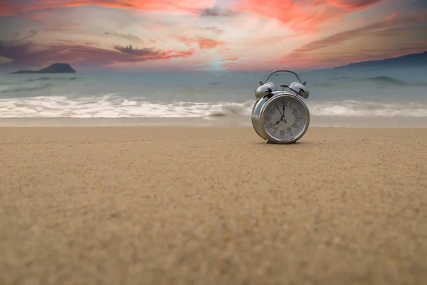 Orologio analogico che segna il tempo delle maree nella sabbia sulla riva della spiaggia con copia del tempo Immagine Stock