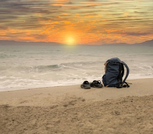 冒険者バックパック海の上に日の出とビーチの砂浜のフリップフロップ — ストック写真