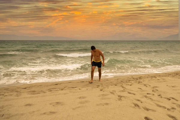 若い白人男性が海から出て海岸の砂浜を歩き — ストック写真
